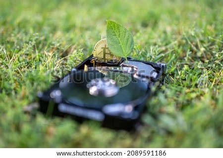 View on a hard disk drive with a bitcoin and a chia leaf representing cryptocurrencies on the grass on a sunny day.