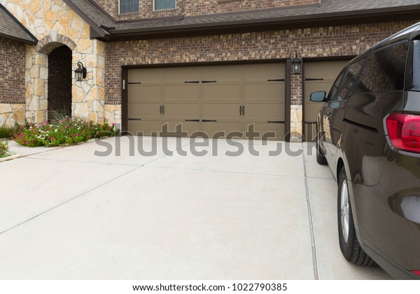 View\
on a house garage from the car side. Parking place near a house and\
entrance to the house with automatic garage\
doors.