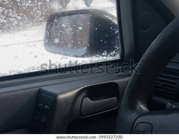 View on left mirror from inside the classic\
car driver\'s seat  at  snow winter\
season