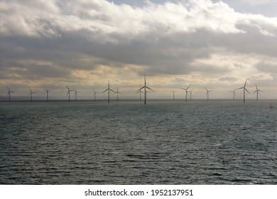 View on the London Array, offshore wind farm which is located 20 kilometres off the Kent coast in the outer Thames Estuary in the United Kingdom during winter time under overcast sky with rainy clouds
