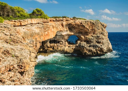 View on rocks with hole and deep blue sea at Cala Sa Nau beach and Cala d'Or city. Mallorca island, Spain Mediterranean Sea, Balearic Islands.