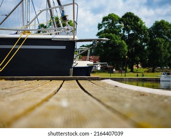 View On Sailboat Moored On Wooden Jetty In The Port, Close Up View On Sailboat Hull And Bow