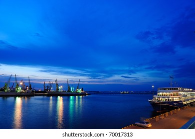 View on seaport with cranes, cargo and passenger ships at the night.