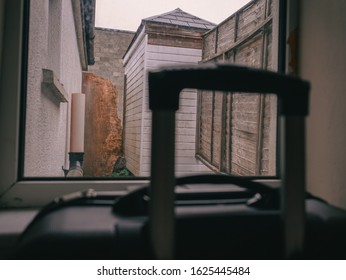 View On A Small Ugly Backyard In A Budget Accommodation, Travel Case By The Window Out Of Focus. Concept Cheap Travel.