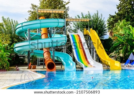View on swimming pool with turquoise clear water and water slide