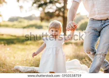 View on toddler. father holds hand daughter enjoy nature and walk in the park. Young family spending time together on vacation, outdoors. father's, baby's day. The concept of family summer holiday