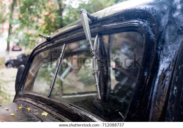 View on windscreen wiper (windshield wiper) of old\
abandoned retro car.