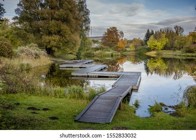 View on a wooden zig-zag pedestrian bridge over the pond on autumn day. National Botanic Garden of Latvia in Salaspils.