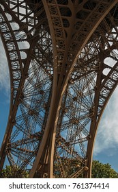 View of one leg’s iron structure of the Eiffel Tower, with blue sky and sunshine in Paris. Known as the “City of Light”, is one of the most impressive world’s cultural center. Northern France.