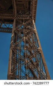 View of one leg’s iron structure of the Eiffel Tower, with sunny blue sky in Paris. Known as the “City of Light”, is one of the most impressive world’s cultural center. Northern France.