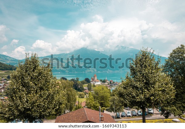 View from one of the railway stations of the Swiss railway. Far away mountains in clouds and haze. Panoramic view of small town on the shores of Lake.