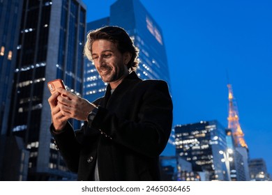 View of one young man using a smartphone at night time with city view landscape in the background.  - Powered by Shutterstock