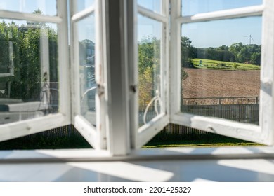 View From Open Window In The Village. White Old Wooden Windows With View On Blue Sky And Green Field. Symbol Of Insouciance, Freedom, Summer Atmosphere. Holiday House, Summer Cottage, Weekend Cottage.