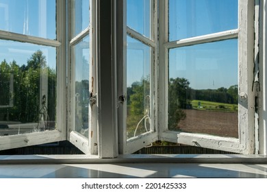 View From Open Window In The Village. White Old Wooden Windows With View On Blue Sky And Green Field. Symbol Of Insouciance, Freedom, Summer Atmosphere. Holiday House, Summer Cottage, Weekend Cottage.