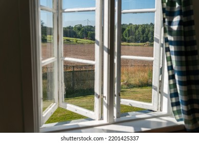 View From Open Window In The Village. White Old Wooden Windows With View On Blue Sky And Green Field. Symbol Of Insouciance, Freedom, Summer Atmosphere. Holiday House, Summer Cottage, Weekend Cottage.