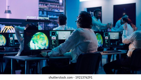 View of operators and flight director using computers then applauding and shaking hands after successful launch of rocket - Shutterstock ID 1921376291