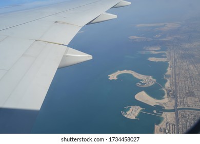 View out of a plane window of a coastline with beautiful twisting land formations and islands.