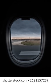 View outside from inside an airplane with clouds and horizon with airport runway