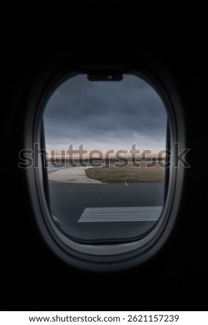 View outside from inside an airplane with clouds and horizon with airport runway