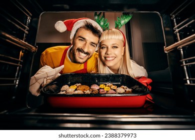 View from the oven of jolly couple baking gingerbread cookies at home on christmas and new year's eve while smiling at the camera. - Powered by Shutterstock