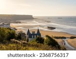 View over Arromanches beach and Cap Manvieux in Normandy, France, at sunset with remains of the WWII artificial Mulberry harbour lying on the sand and in the sea.