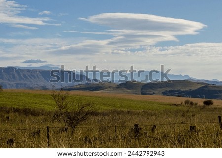 View over the distant blue mountains of the Drakensberg Mountain Range in South Africa, with Lenticular clouds forming above it. 