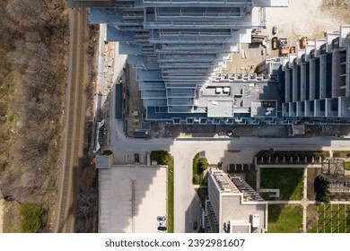 View over empty construction site, cranes and machinery, car traffic in city downtown. Aerial top view. New residential housing construction concrete framing. Urban multi-storey apartment building.