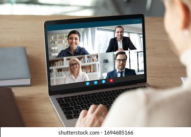 View over female shoulder at computer webcam screen view of four different age and ethnicity business people negotiating distantly using video conference app, video call virtual communication concept - Powered by Shutterstock