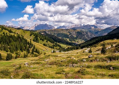 View over the green mountains and rocks of the Dolomites during a beautiful summer day. The winding road leads you to the valley. Mountain pass, Sella pass, dolomites Italy.
