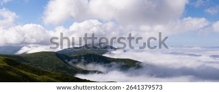 A view over mountains and clouds from the top of a mountain.