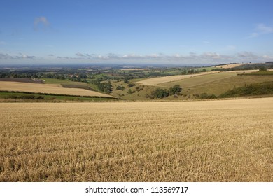 a view over a patchwork autumn fieldscape towards the hazy vale of york from a stubble field high on the yorkshire wolds under a clear blue sky