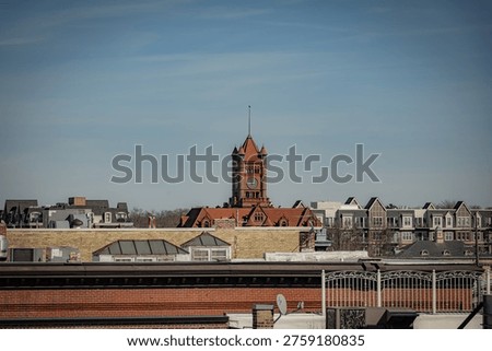 View over rooftops of the historic former DuPage County Courthouse clock tower with its distinctive red terracotta roof in Wheaton Illinois under a clear blue sky