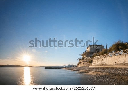 View over the sea into the sunset landscape shot with the historical landmark Byzantine Tower of Prosphorion at the 
Coast of Ouranoupoli, Thessaloniki, Central Macedonia, Greece