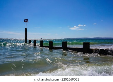 View Over Sea At UK Beach. Coastal Scene With Wave Break Groyne. Blue Skies Over Dorset Beach In Bournemouth