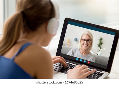 View over shoulder of adult daughter talks by video call with 50s mum. Pc screen view smiling elderly grandmother enjoy virtual chat videoconference with grown up granddaughter. New tech usage concept - Powered by Shutterstock