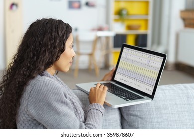 View Over The Shoulder Of A Woman Working On Laptop Balancing It On The Sofa