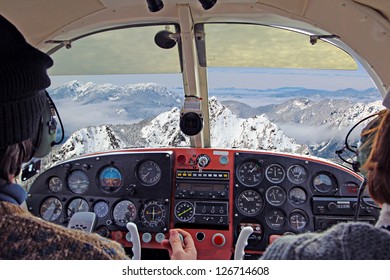 view from over snow covered peaks while flying in small plane - Powered by Shutterstock