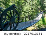 View over Train Wreck Bridge, Whistler, BC, Canada with anchor frames designed to look like locomotive wheels on the Sea To Sky Trail leading to the colorful train wreck box cars from 1956 accident