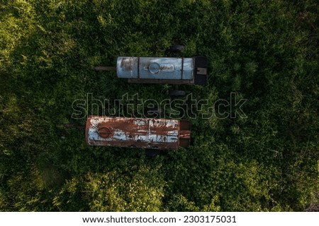 View over two old water bowsers in a field