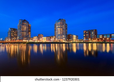 View over water to typically residential apartments towers "de Elementen" at night near the heemkanaal at the suburban Oosterheem, Zoetermeer, the Netherlands during dusk