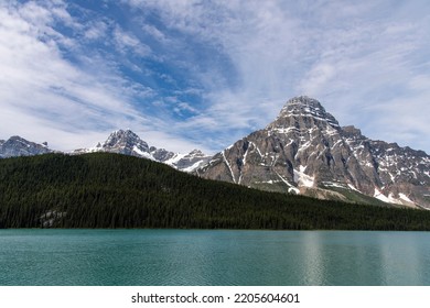 View Over Waterfowl Lakes, Alberta, Canada With In Background The Snow Covered Mountain White Pyramid In The Canadian Rockies Of Banff National Park Against A White Clouded Blue Sky