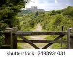 View over a wooden gate with Dover Castle. Dover Castle is a medieval castle in Dover, Kent, England and is Grade I listed. It was founded in the 11th century and has been described as the "Key to Eng