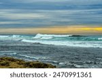 VIEW OF THE PACIFIC OCEAN FROM THE SHORES OF THE LA JOLLA COASTLINE WITH A BEAUTIFUL SKY AND SUNSET WITH WAVES COMING ON SHORE NEAR SAN DIEGO CALIFORNIA