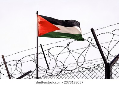 View of palestinian flag behind barbed wire against cloudy sky. border post on the border of palestine. The checkpoint at the embassy of the country. the Palestinian-Israeli border.