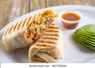 A view of a panini pressed breakfast burrito, in a restaurant or kitchen setting.