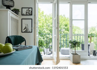 View of a park from a balcony with open door and close-up of apples on a table in a daily room interior - Shutterstock ID 1192401553