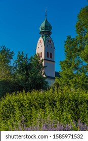 view from the park to the clock tower of the city church in rosenheim, bavaria