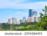 View from the park to the downtown of the city with high buildings, skyscrapers through the green branches of summer park. Center of Edmonton, Alberta, Canada.