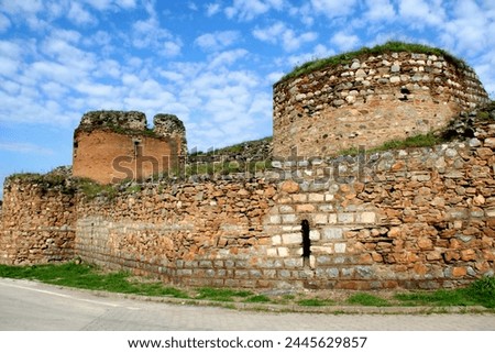 View of the part of a wall surrounding a historic part of the city with round towers against a blue cloudy sky in Iznik, Turkey
