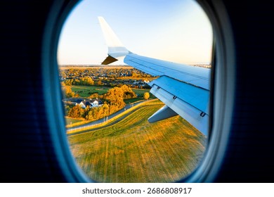 View from passenger plane window wing and jet engine over a road and fields in Denmark at sunrise, Copenhagen, travel concept.
